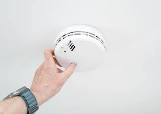 Person testing smoke alarm